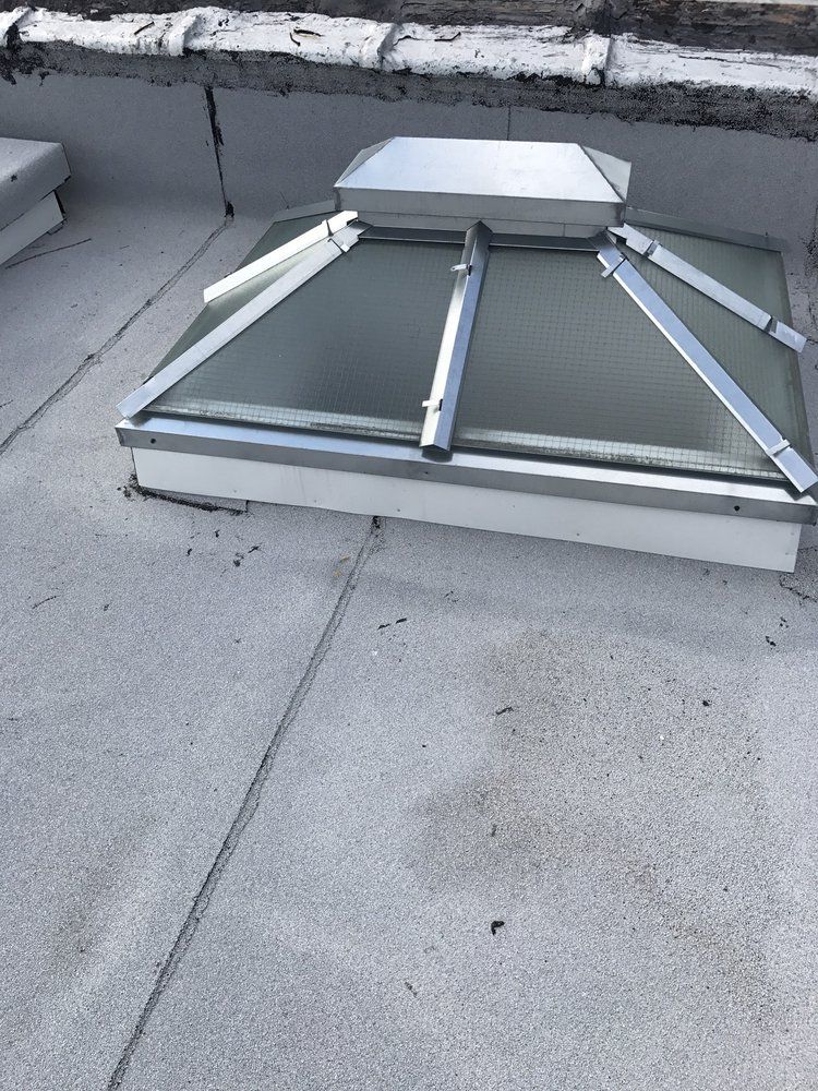 A skylight is sitting on top of a concrete roof.
