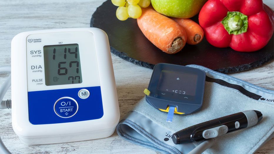 blood pressure gauge next to healthy vegetables and fruit