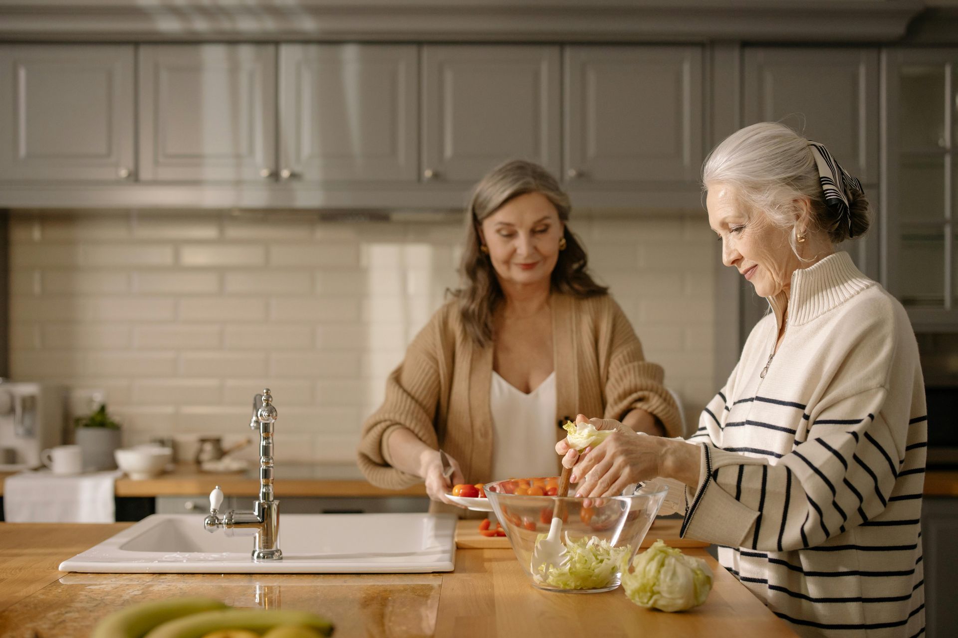 Two senior women preparing food.