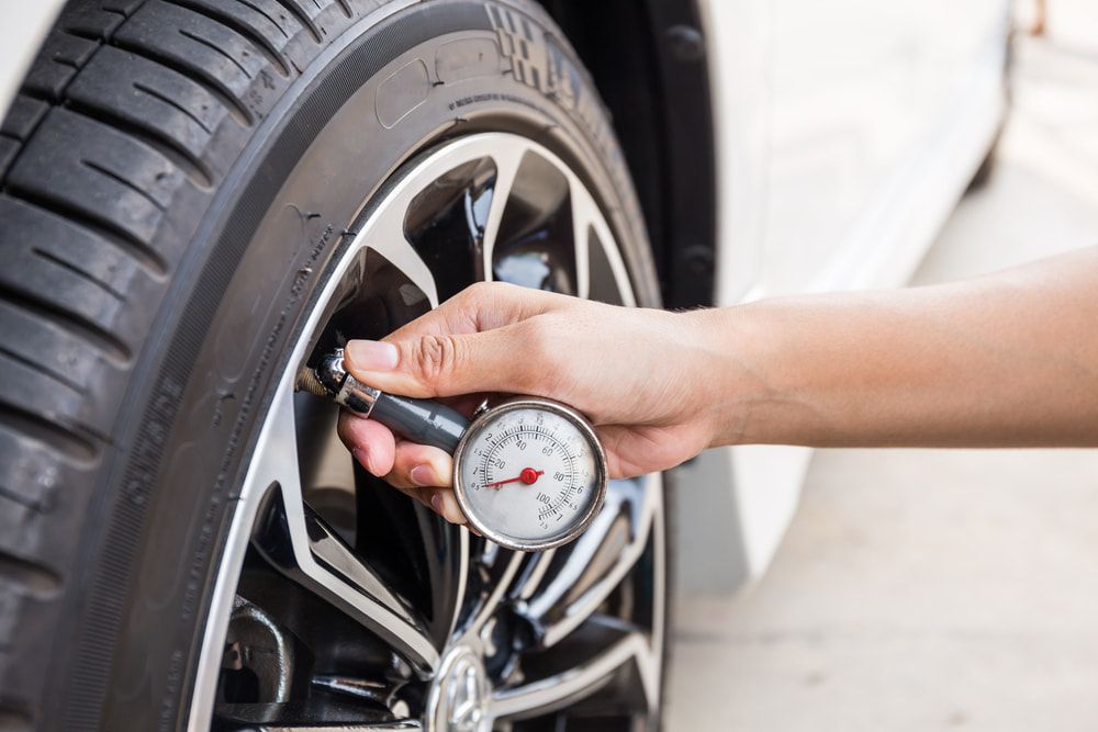 A Person is Checking the Pressure of a Tire With a Gauge — Powerhouse Auto Repairs Bundaberg in Bargara, QLD
