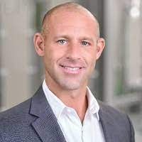 A man in a suit and white shirt is smiling for the camera.