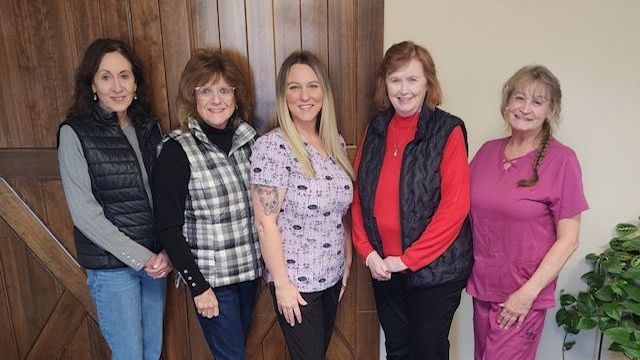 A group of women are posing for a picture in front of a wooden door.