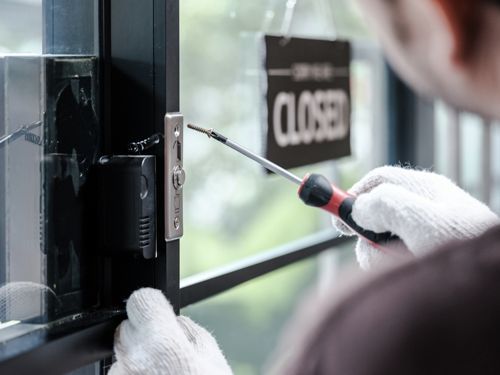 A Man Is Installing A New Door Lock In A Store - Bolingbrook, IL - Master Locksmithing Inc
