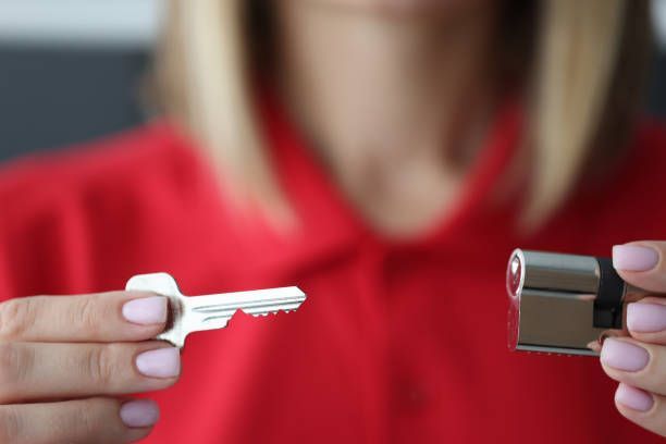 A Woman Is Holding A Key And A Key Cylinder - Bolingbrook, IL - Master Locksmithing Inc