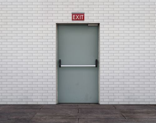 A White Brick Wall With An Exit Sign Above The Door - Bolingbrook, IL - Master Locksmithing Inc