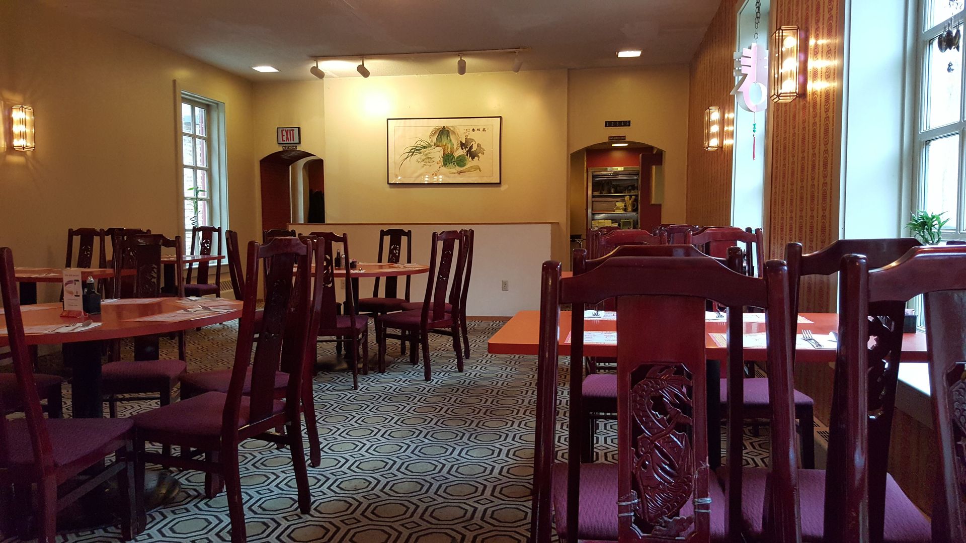 Chinese restaurant interior with red chairs, tables, and floral carpet.