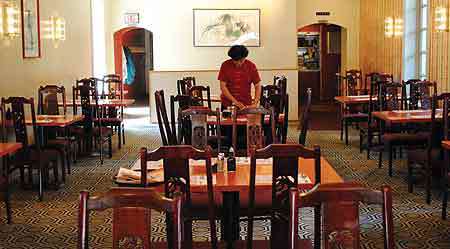 A woman is standing at a table in a restaurant.