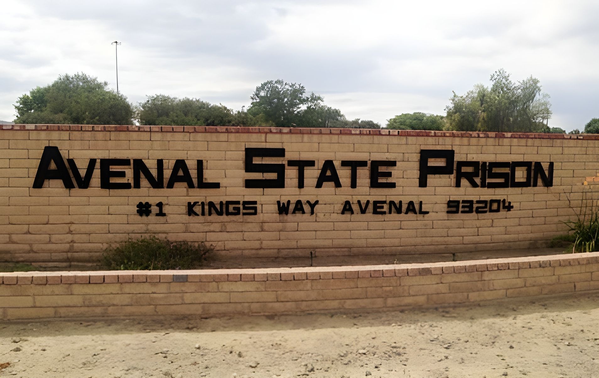 Sign for Avenal State Prison: brick wall with black letters. Address is #1 Kings Way, Avenal, CA 93204.