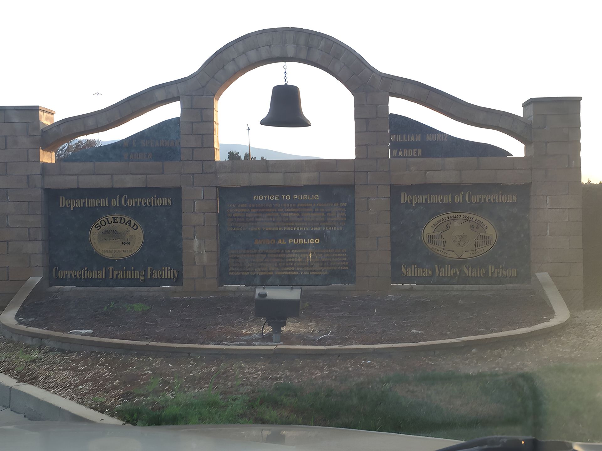 Stone archway with bell and plaques, marking a border.