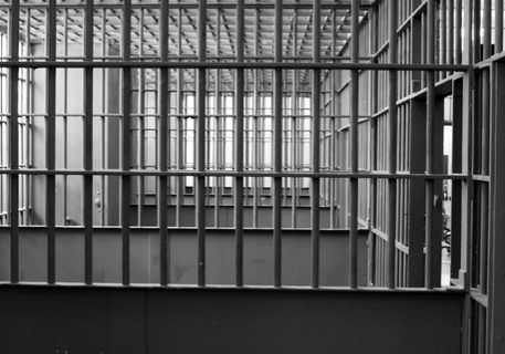 Empty prison cells with metal bars.