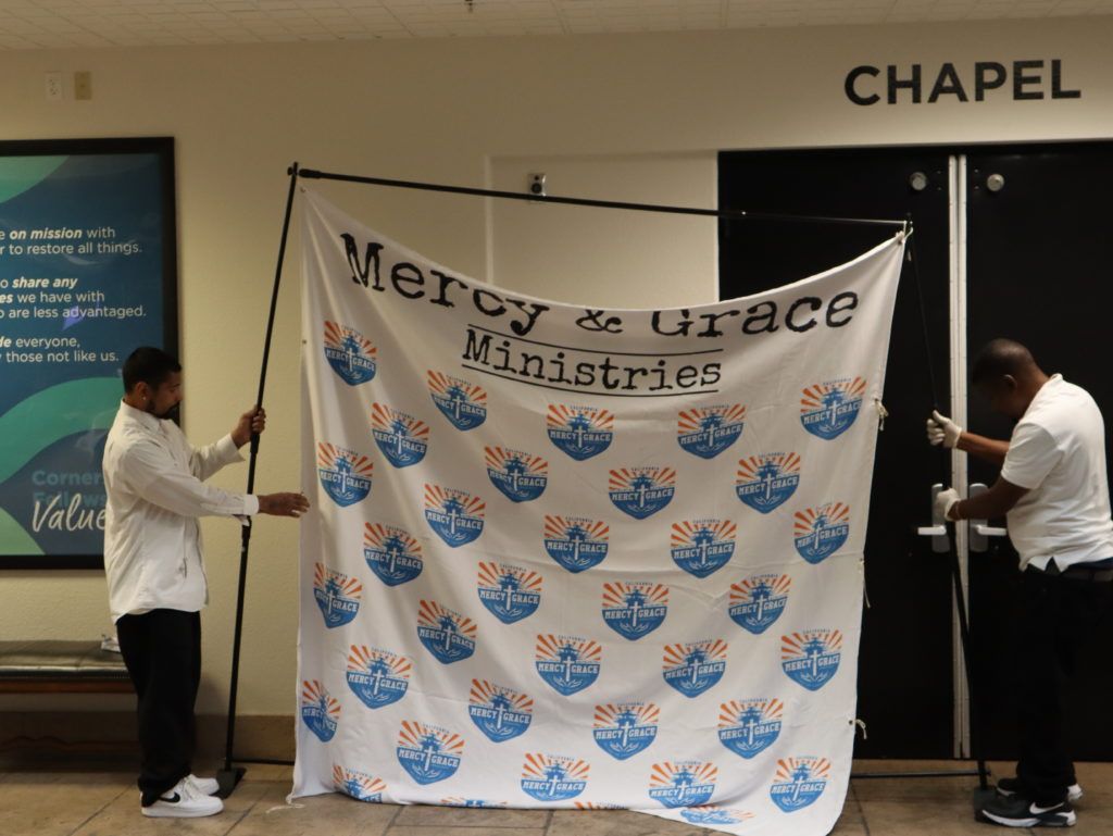 Two people hanging a banner that says