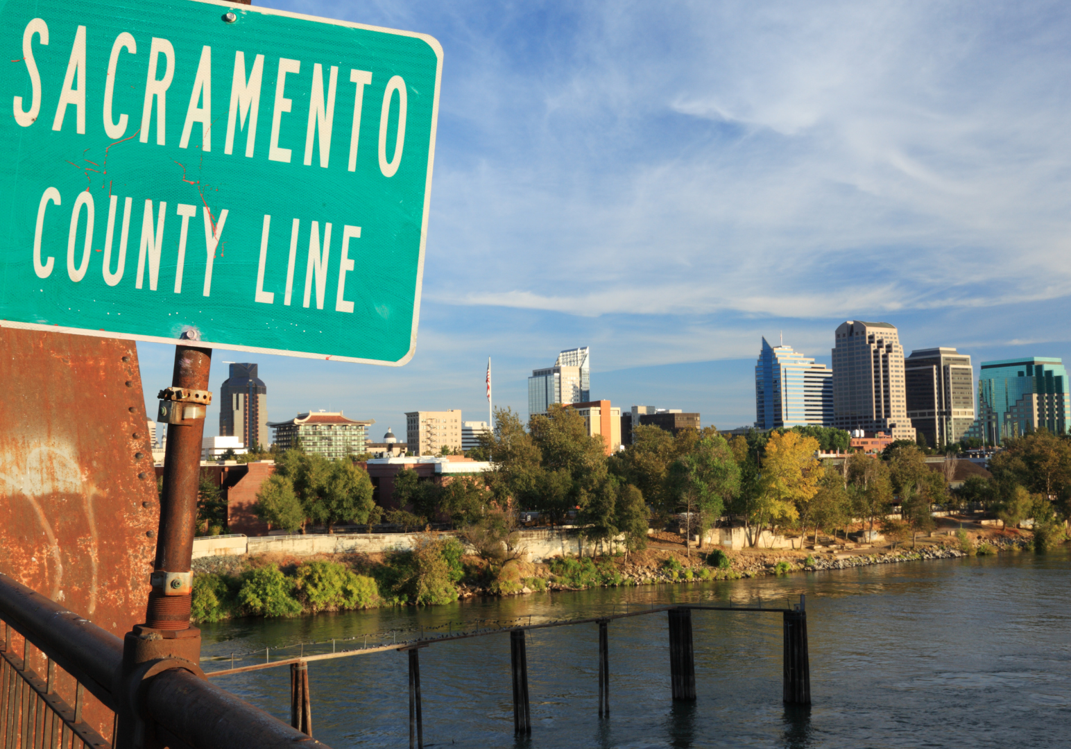 Sacramento County Line sign with cityscape and river on a sunny day.