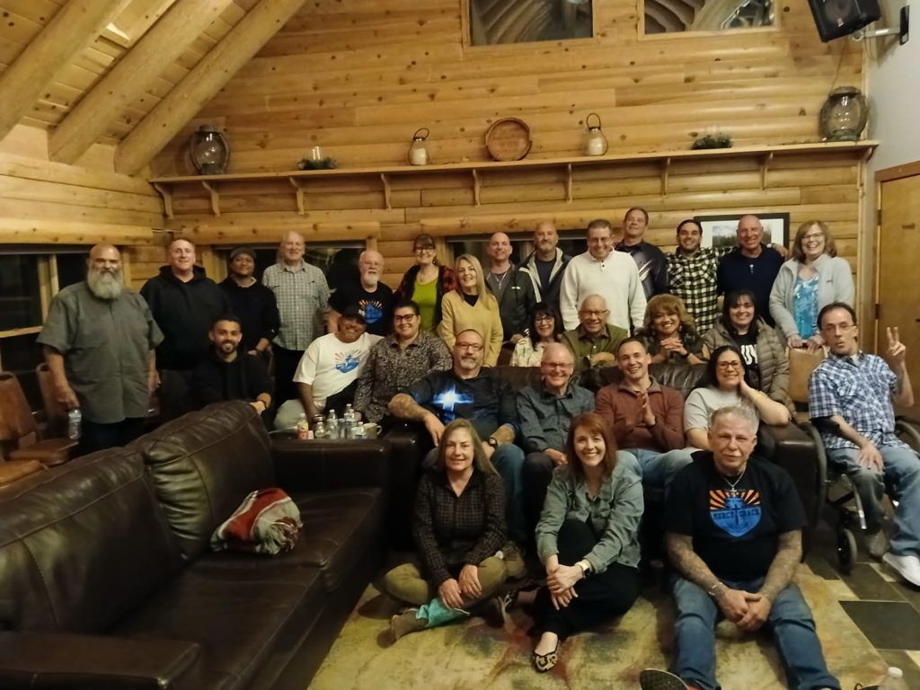 Group of people posing for a photo inside a log cabin.