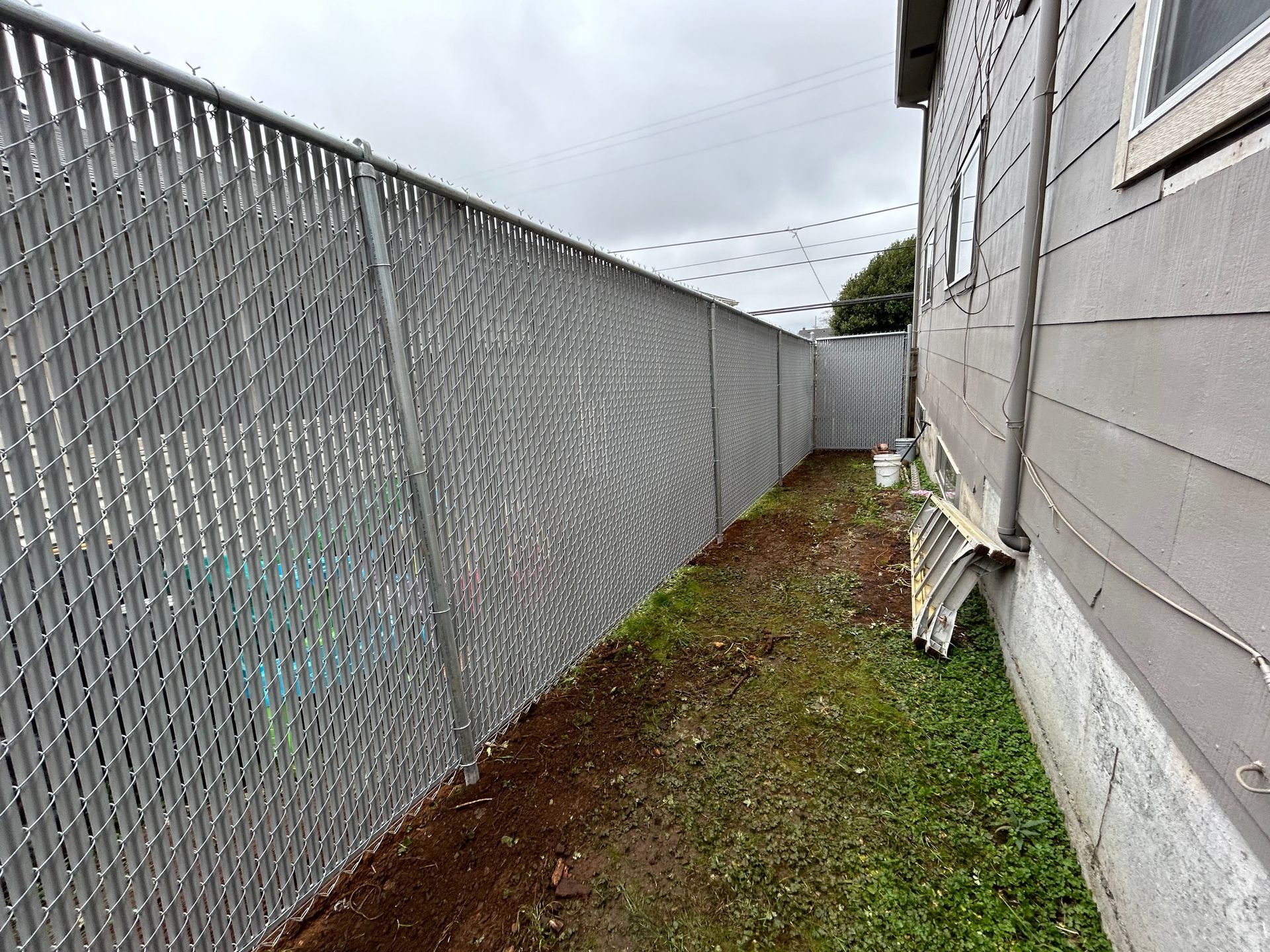 There is a chain link fence in the backyard of a house.