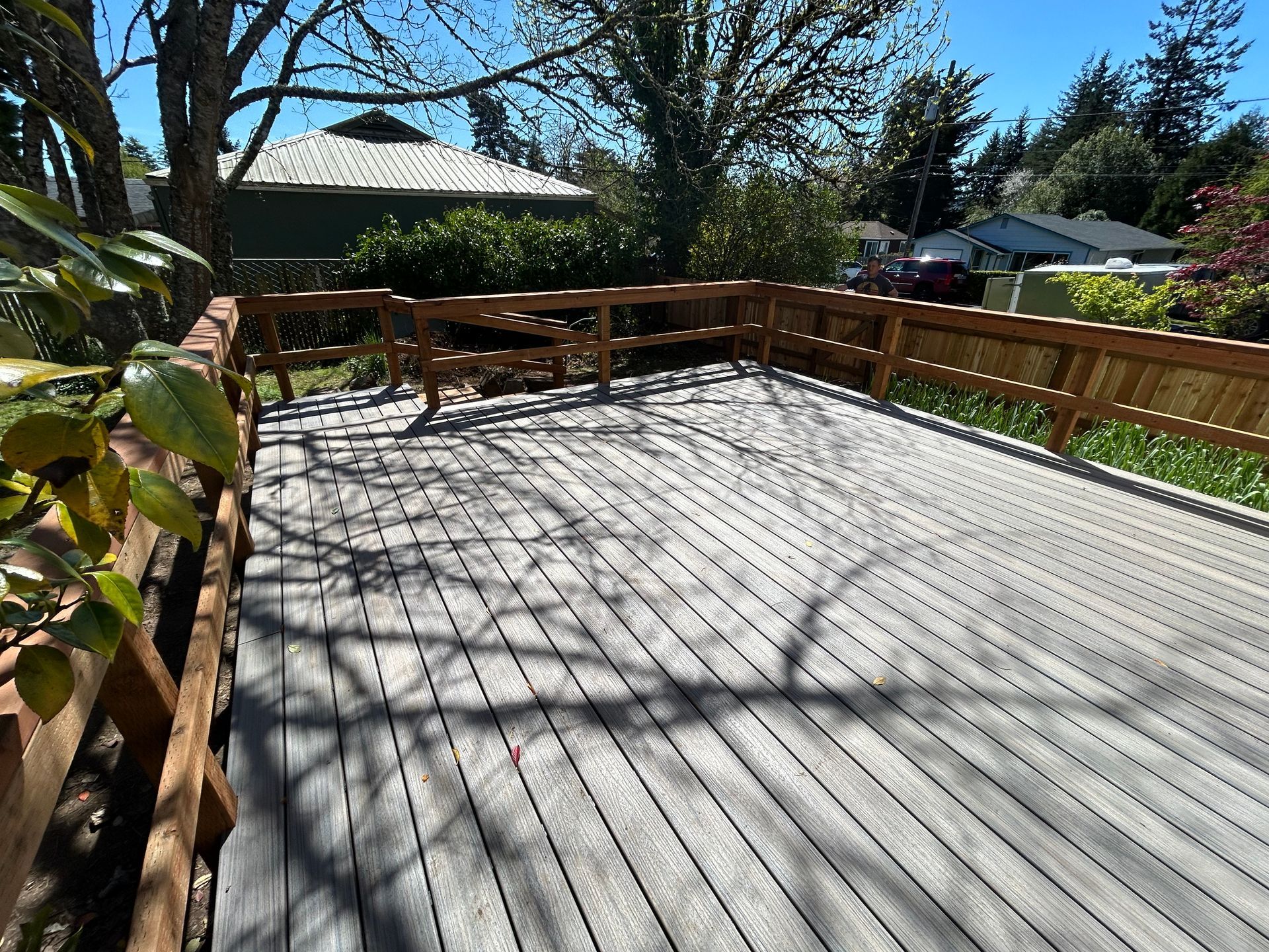 A wooden deck with a wooden railing and a fence surrounding it.