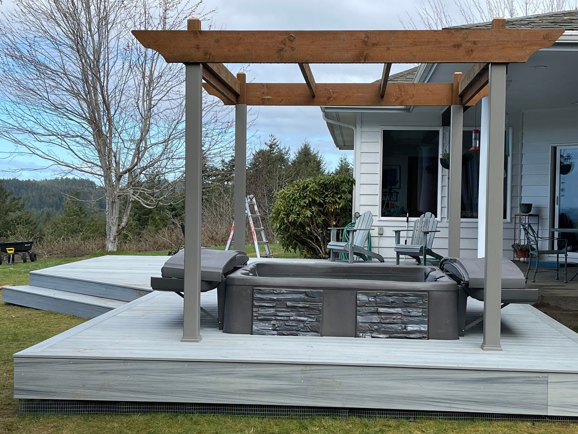 There is a hot tub on the deck under a pergola.