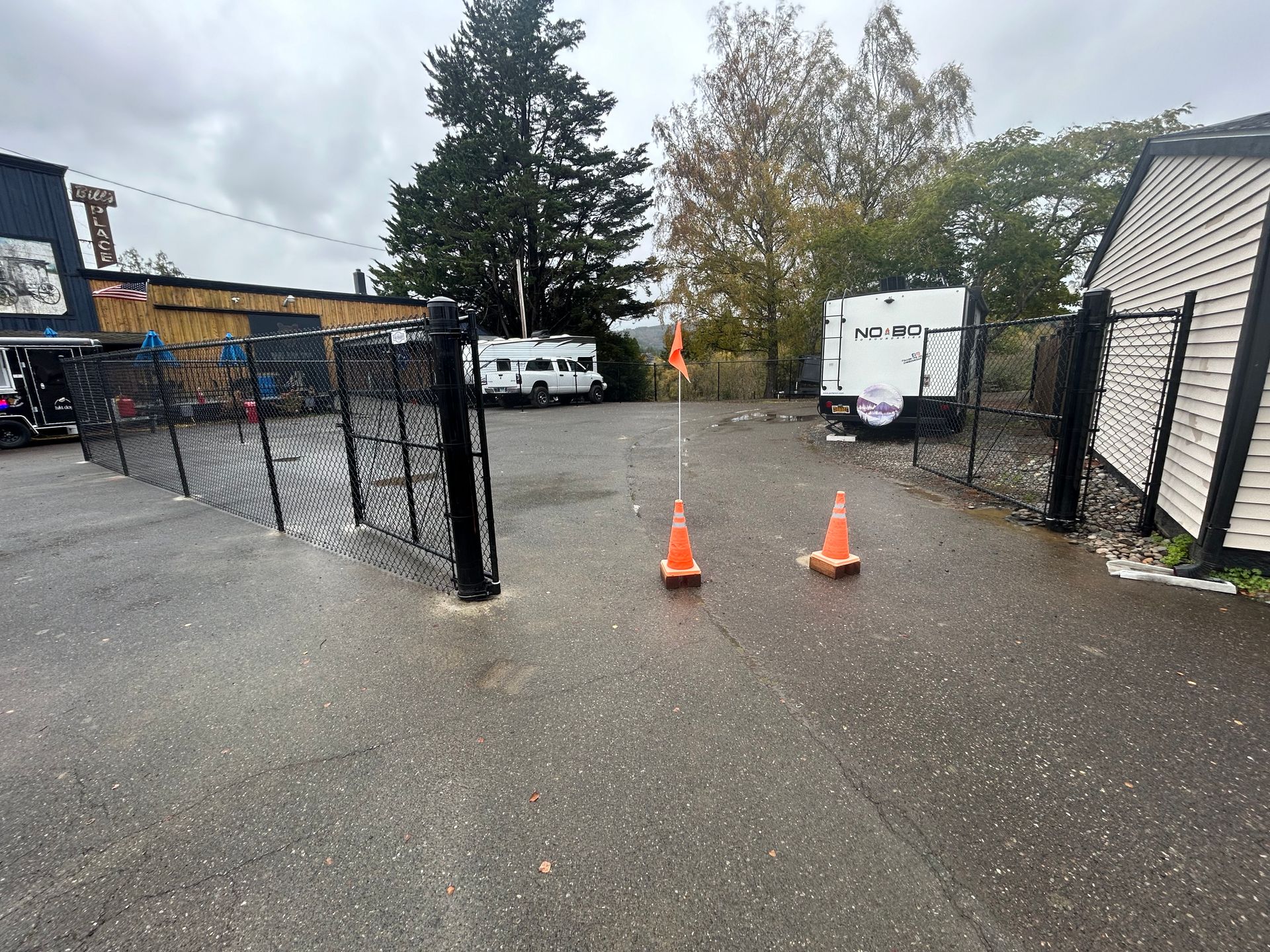 There are two orange cones in the middle of a parking lot.