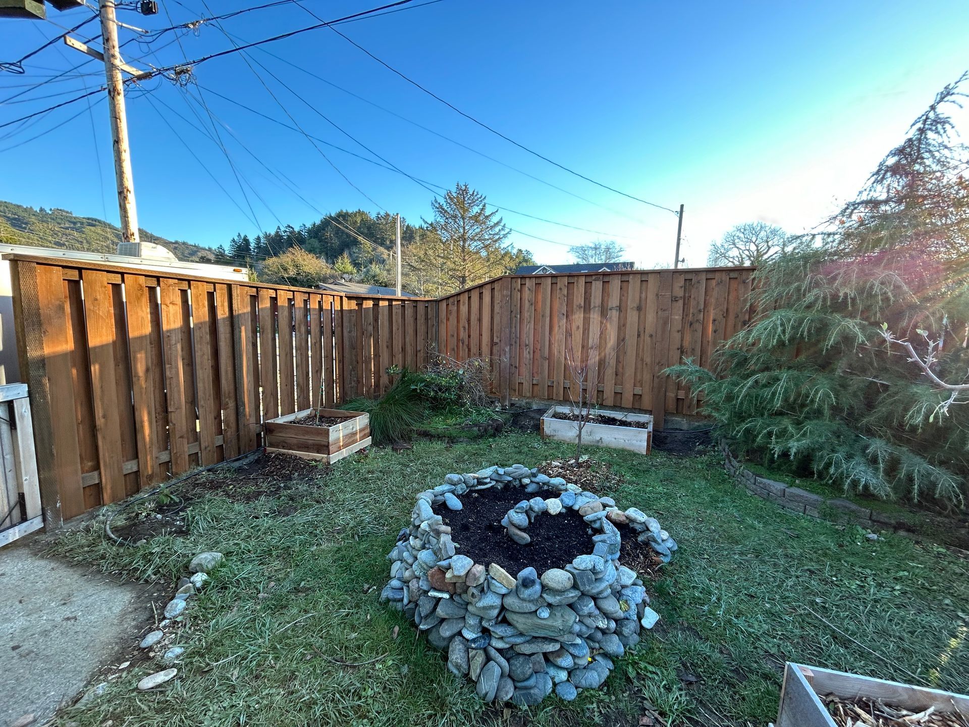 A backyard with a wooden fence and a fire pit.