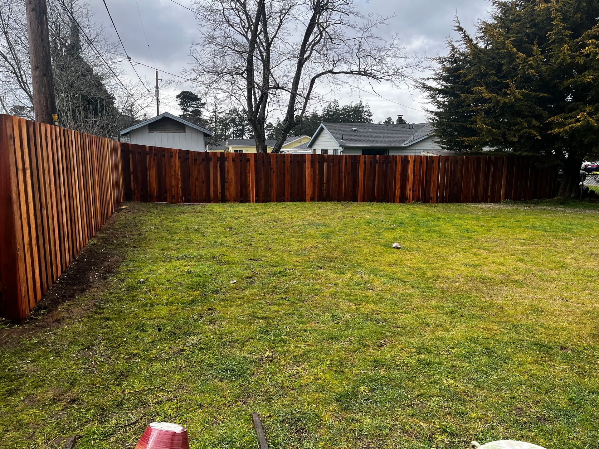 A wooden fence surrounds a lush green yard.
