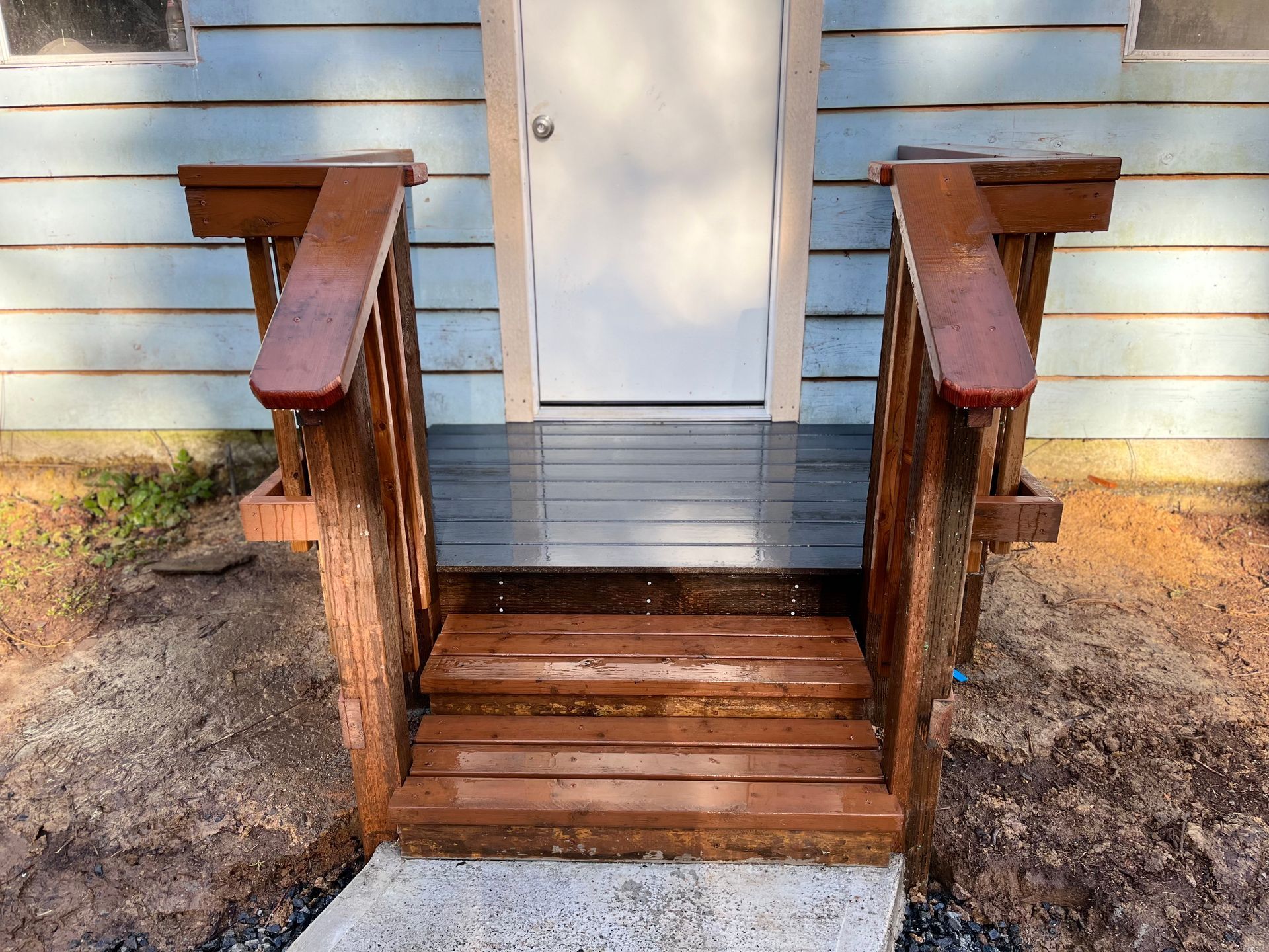 A wooden porch with stairs leading up to the front door of a house