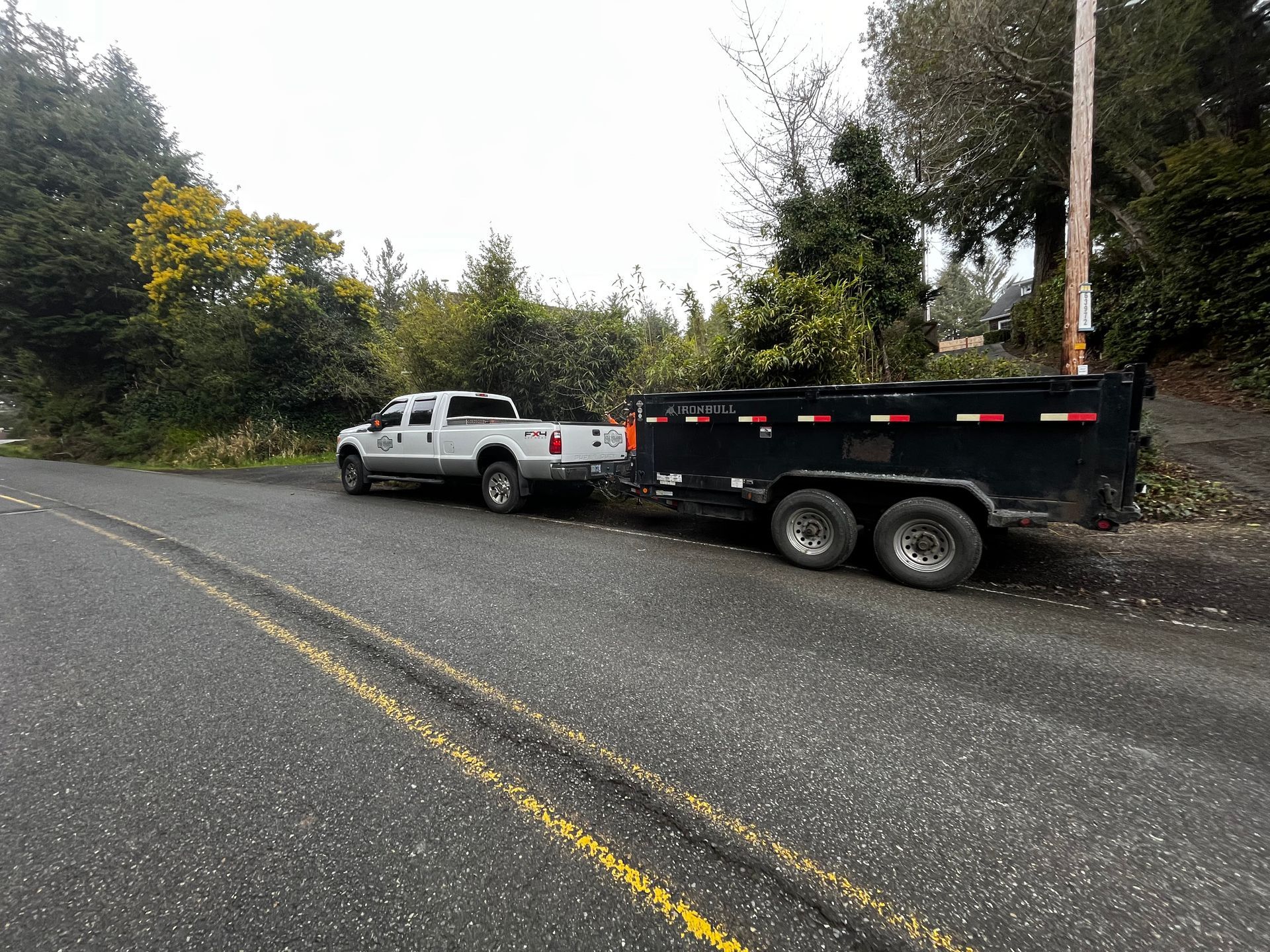 A white truck is pulling a black trailer down a road.