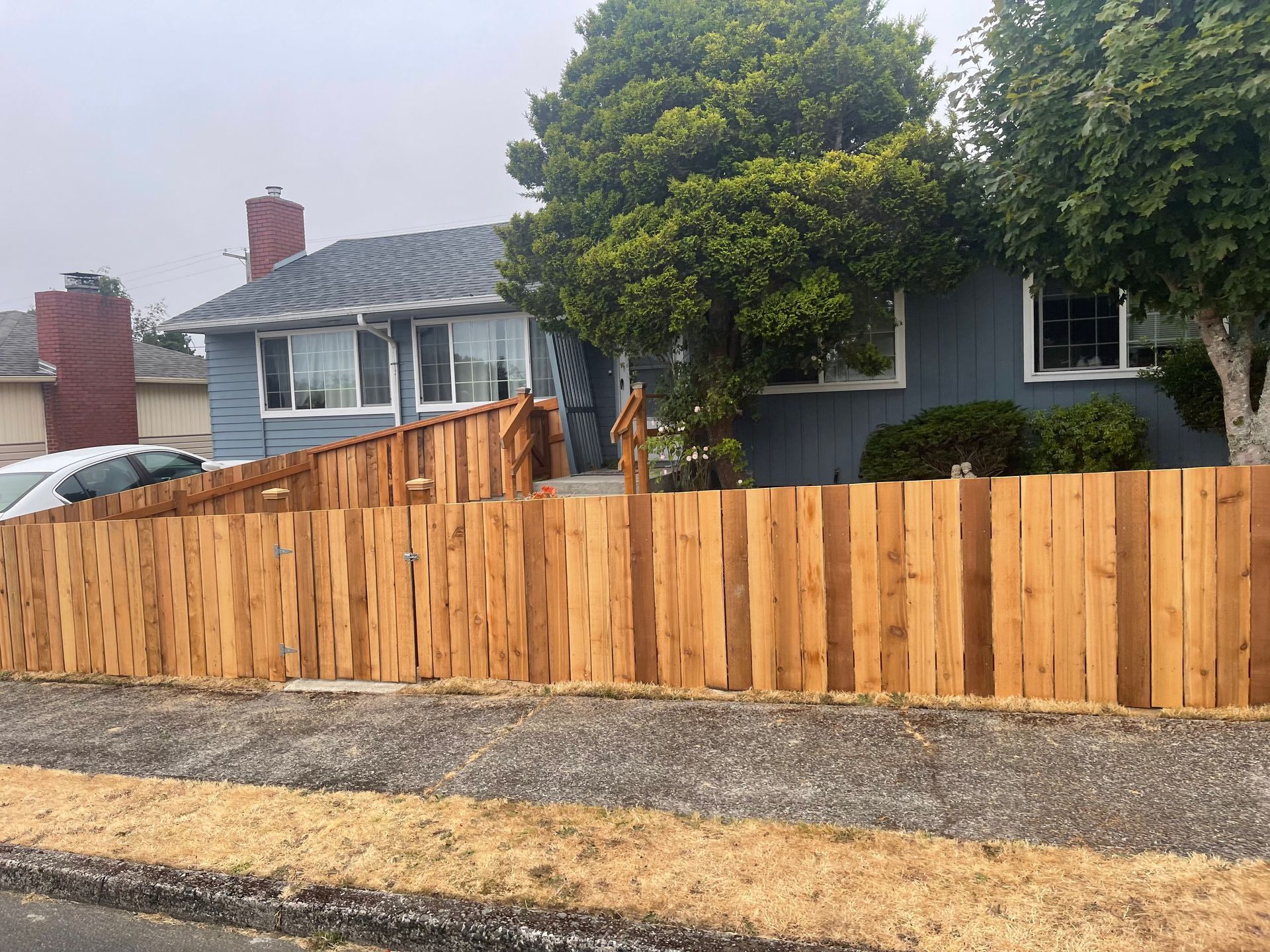 A wooden fence is in front of a blue house.