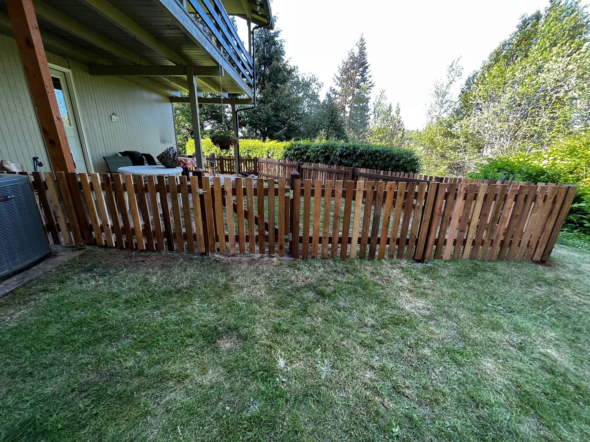 A wooden fence is sitting in the middle of a lush green yard.