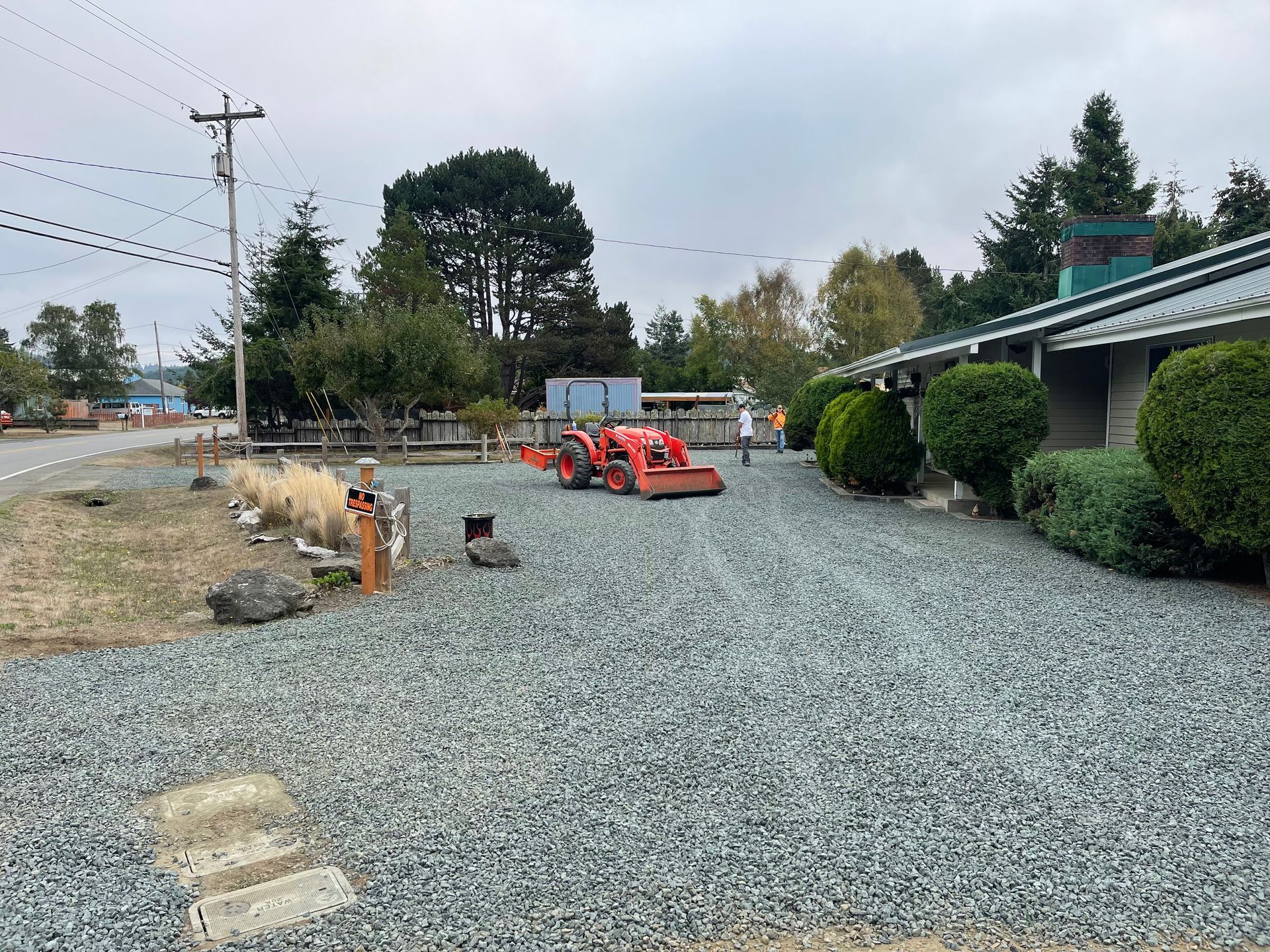 A tractor is parked in a gravel lot in front of a house.