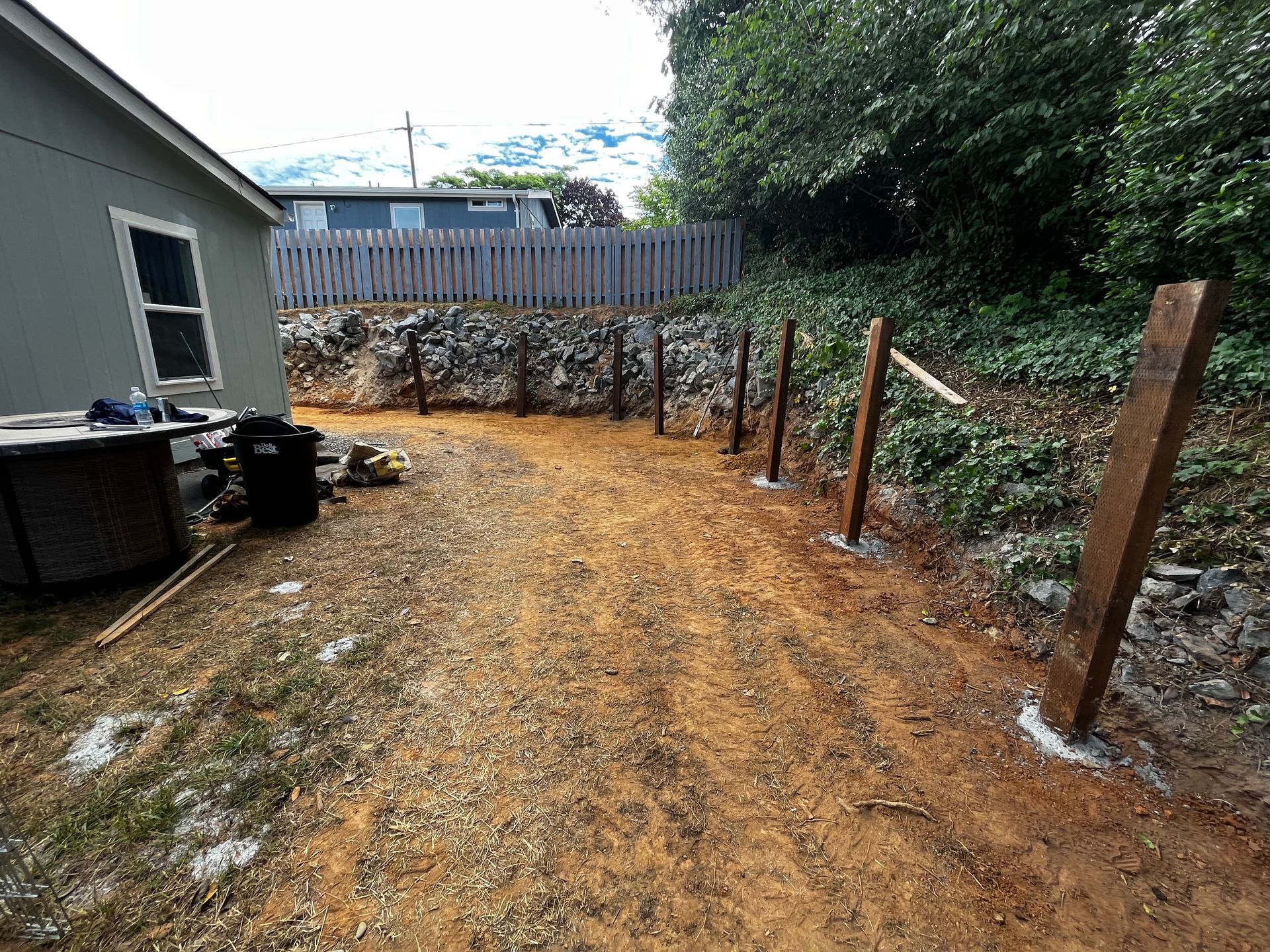 A dirt road leading to a house with a fence in the background.