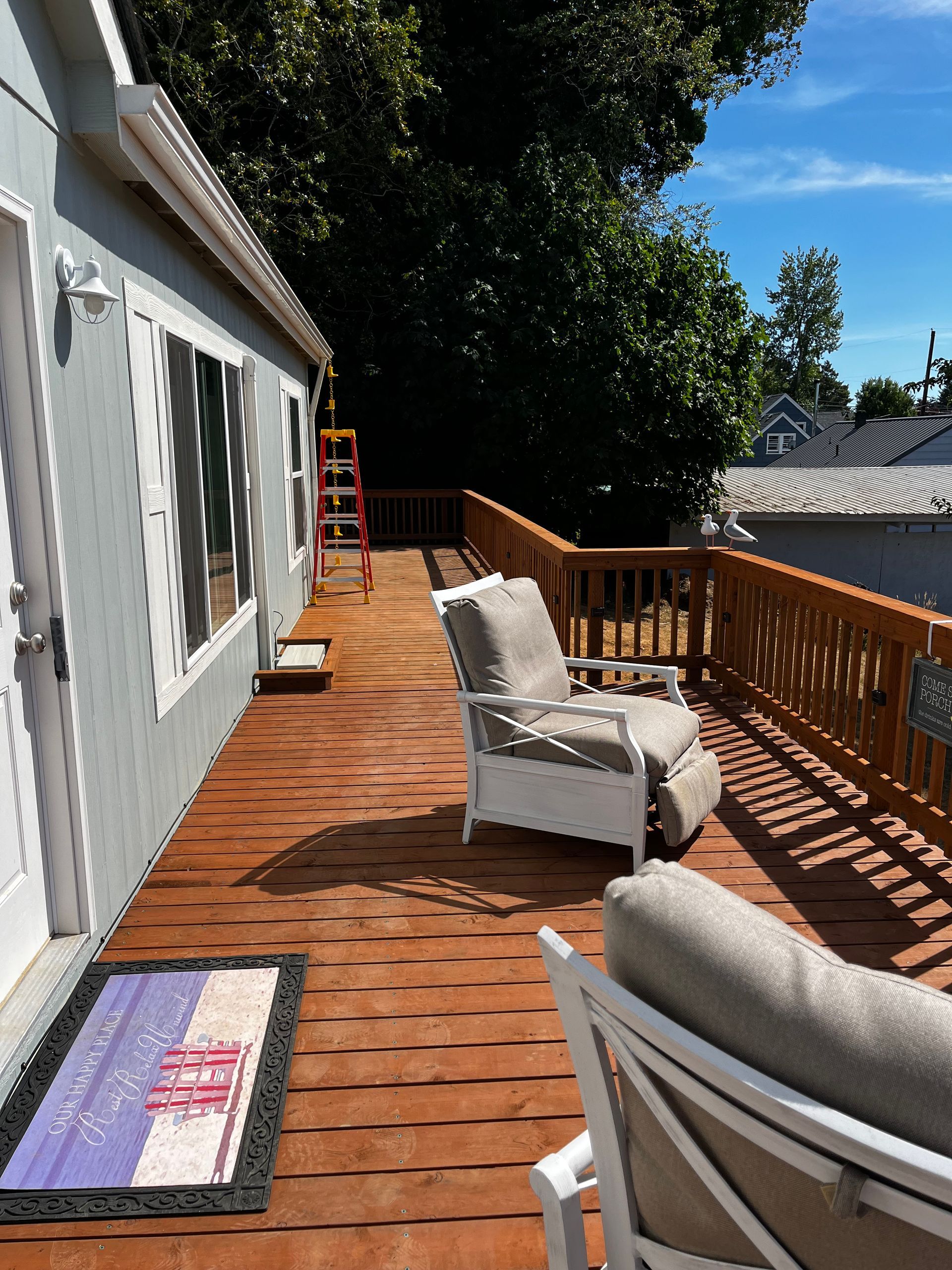 A wooden deck with chairs and a rug on it