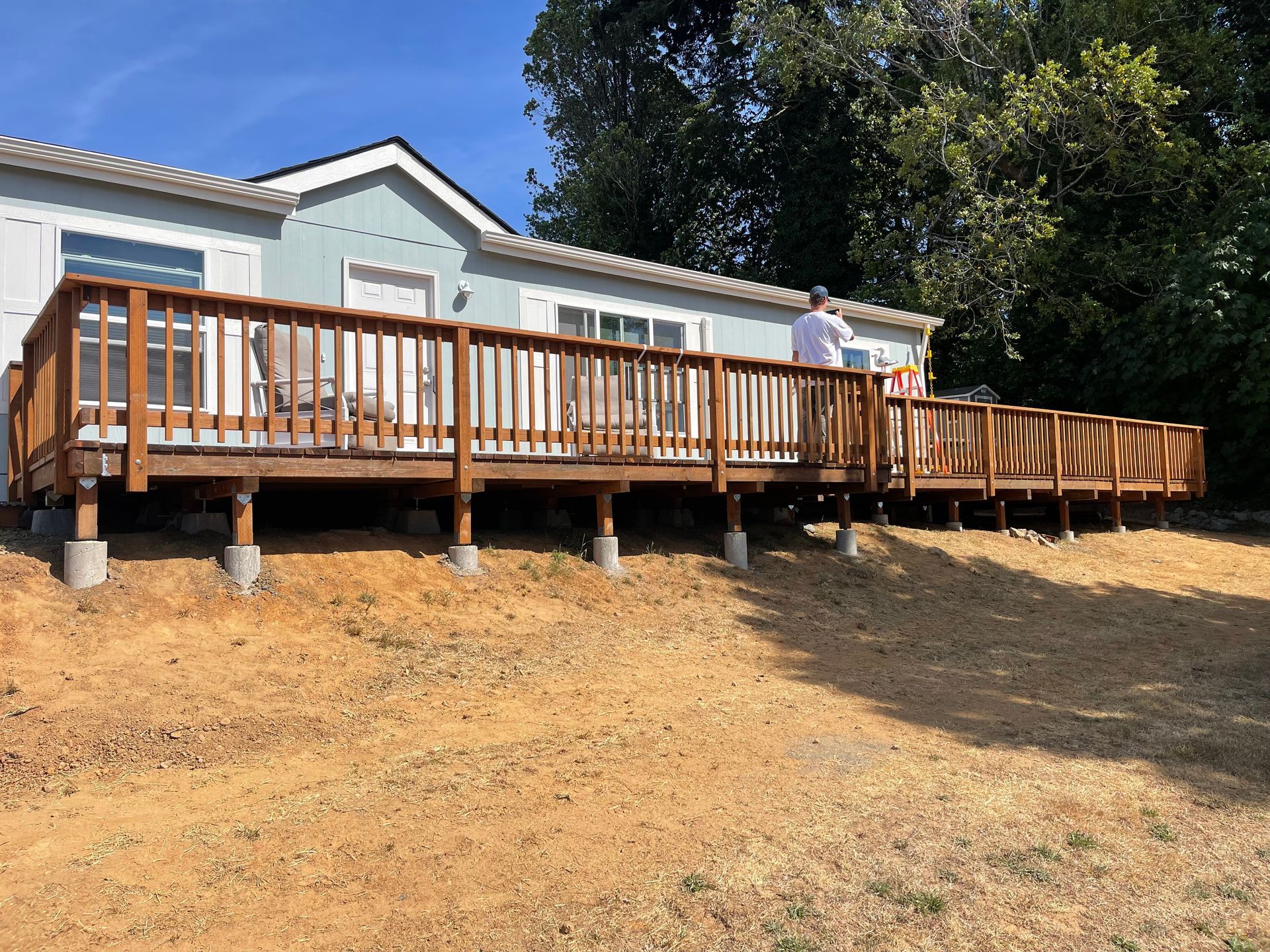 A man is standing on a wooden deck in front of a house.