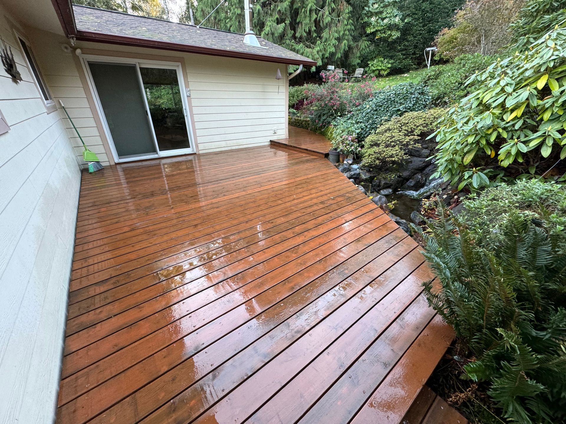 A wooden deck in front of a house with a sliding glass door.