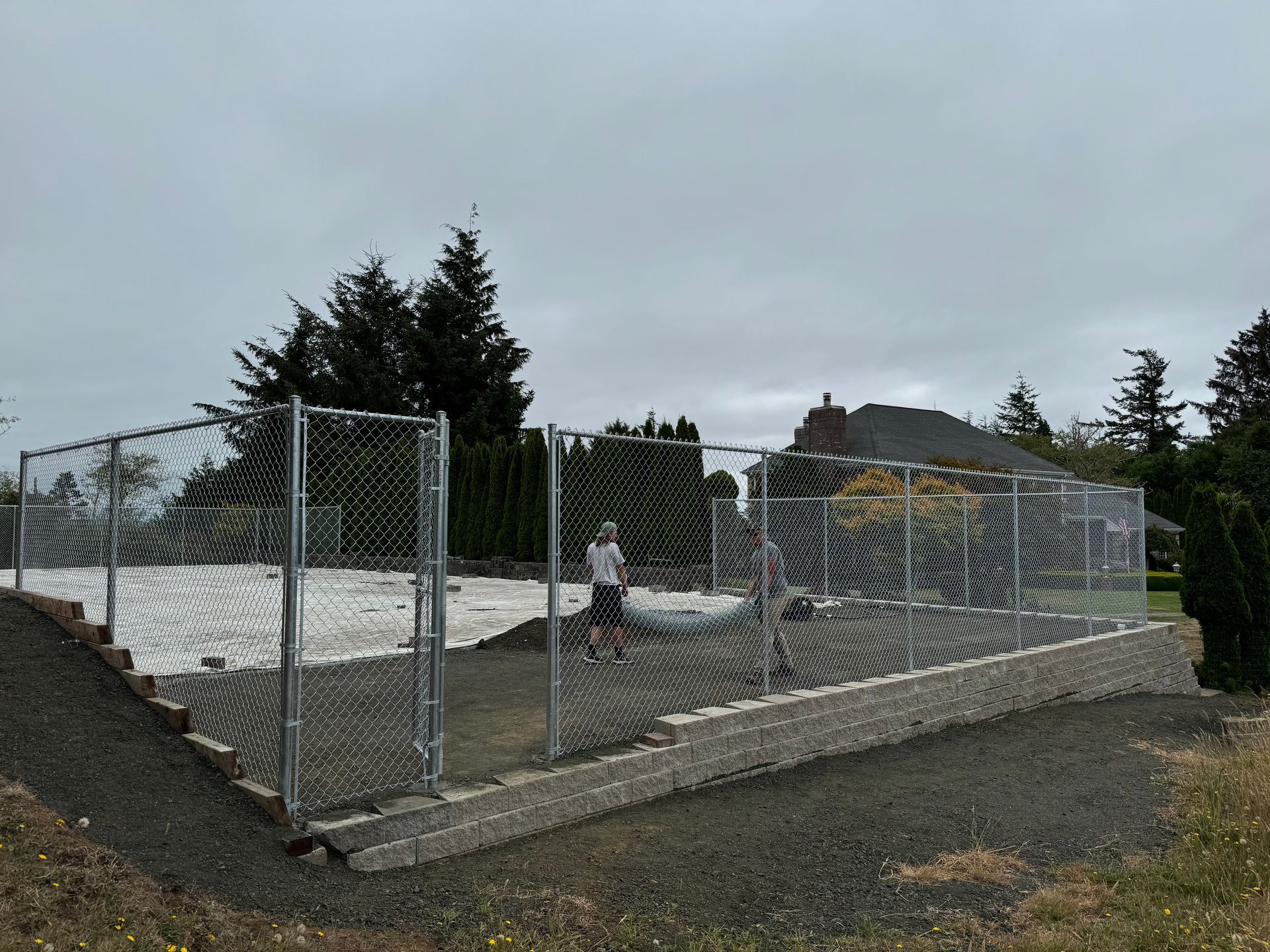 A man is standing in front of a chain link fence.