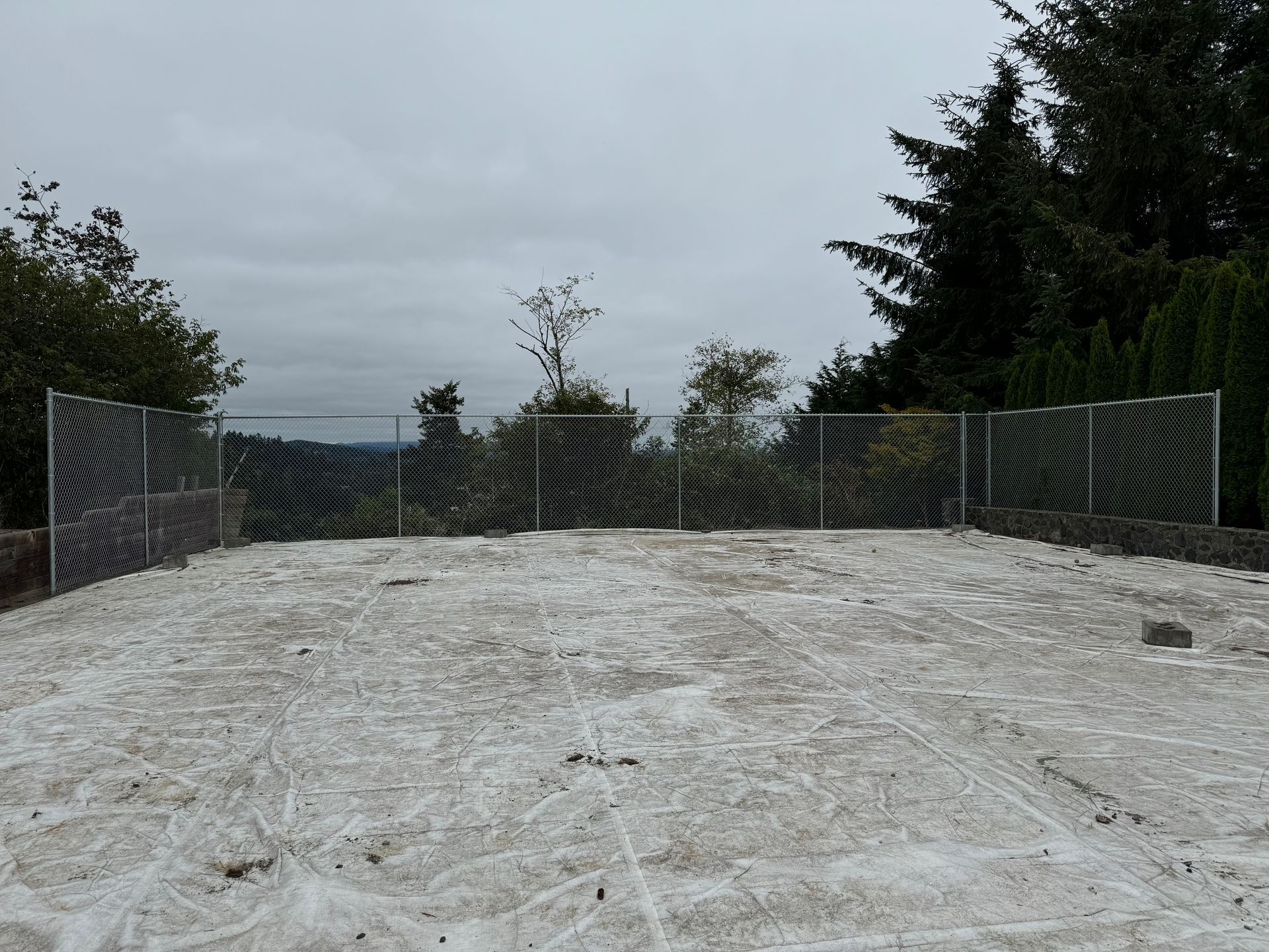 A snowy field with a chain link fence surrounding it