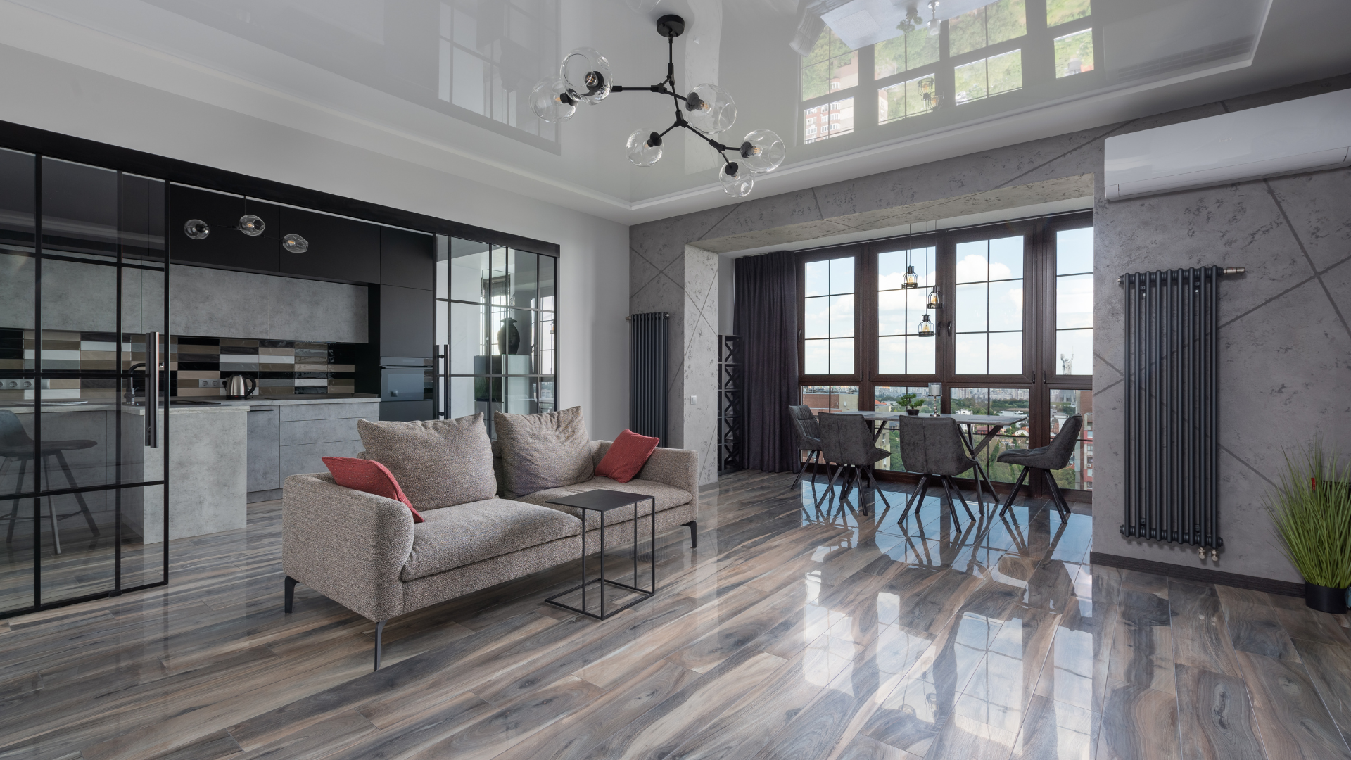 Three paint rollers are sitting on a wooden floor next to a wooden stool.