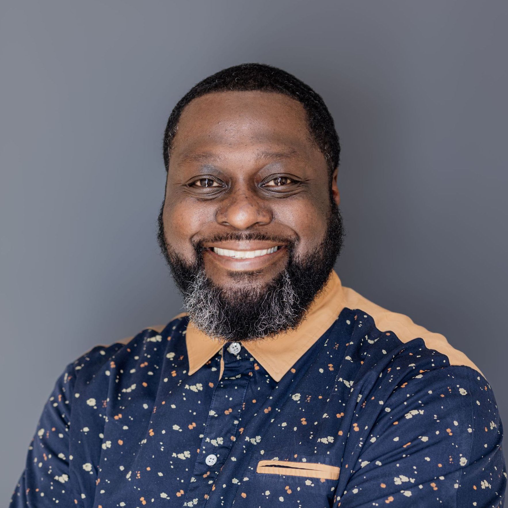 A man with a beard and a blue shirt is smiling for the camera.