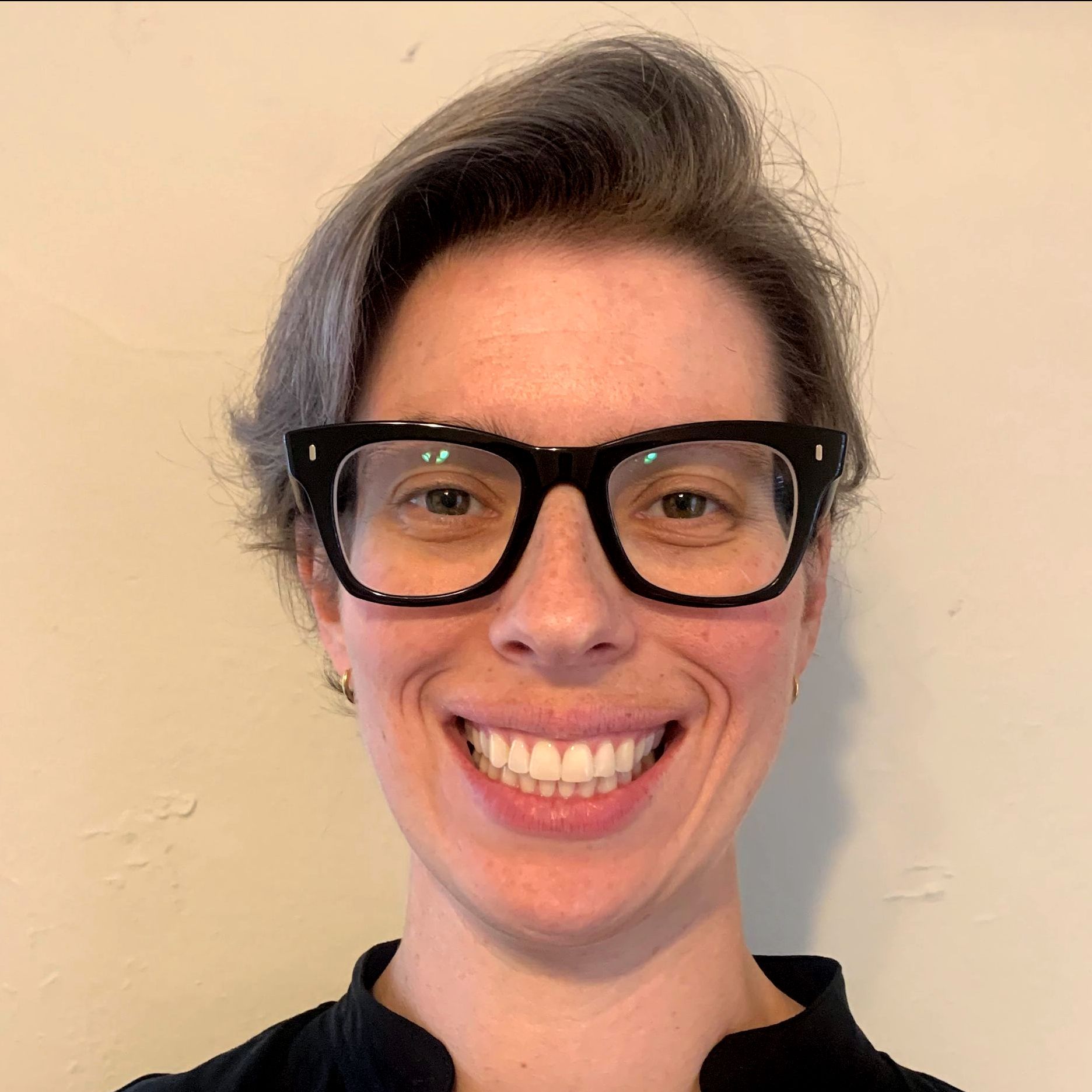 A woman wearing glasses is smiling for the camera.