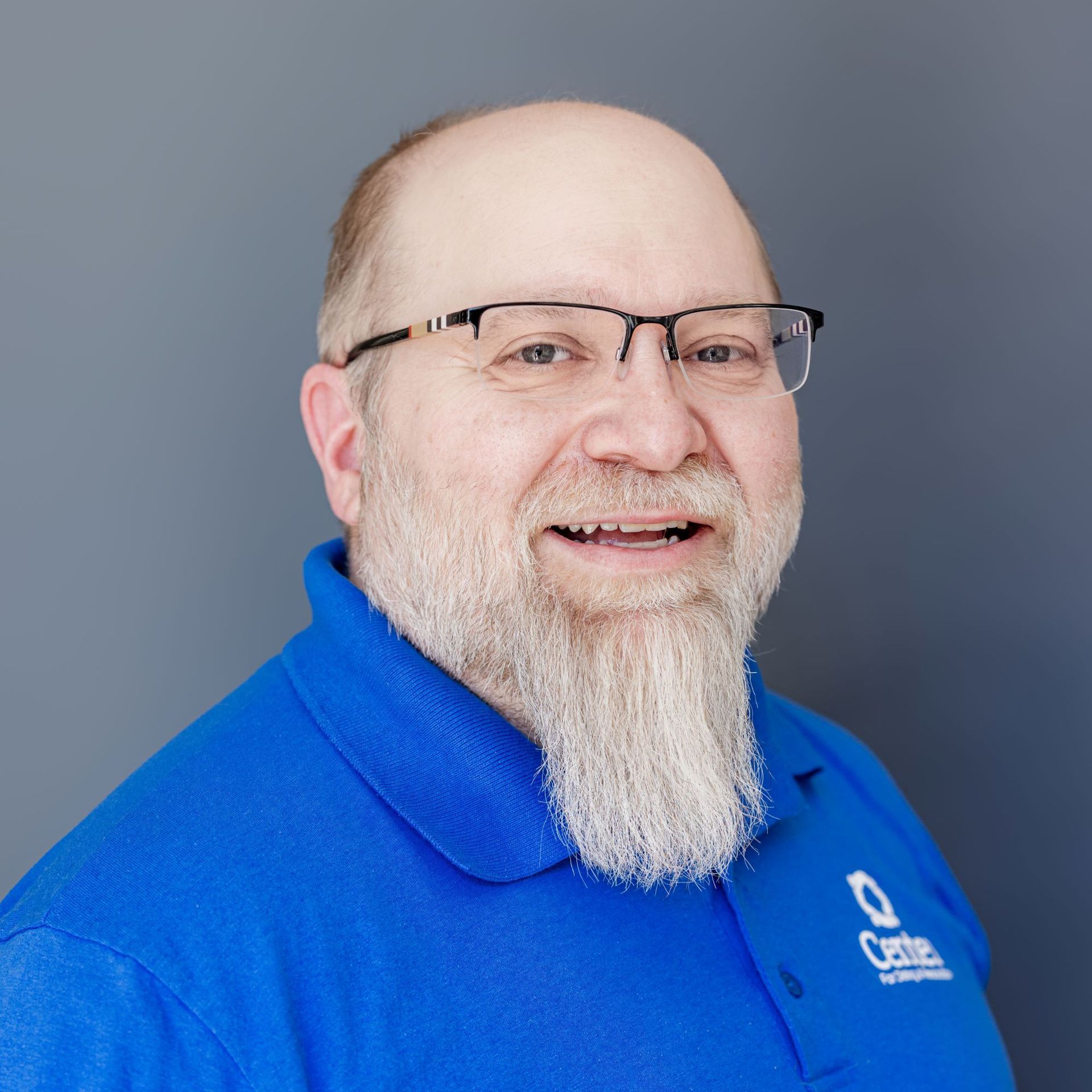 A man with a beard and glasses is wearing a blue shirt.