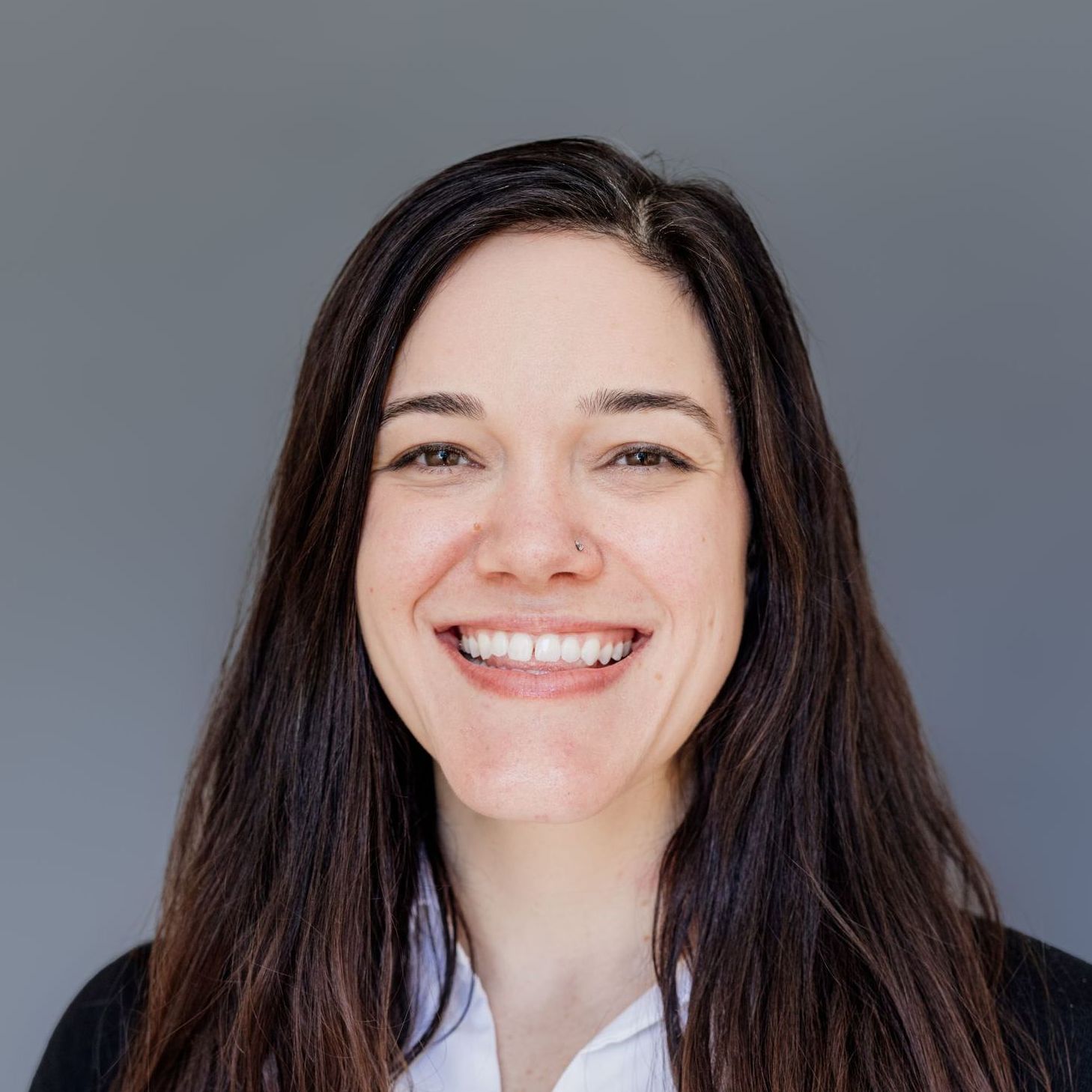 A woman with long brown hair is smiling for the camera.