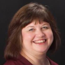 a woman is smiling for the camera and wearing a red shirt .