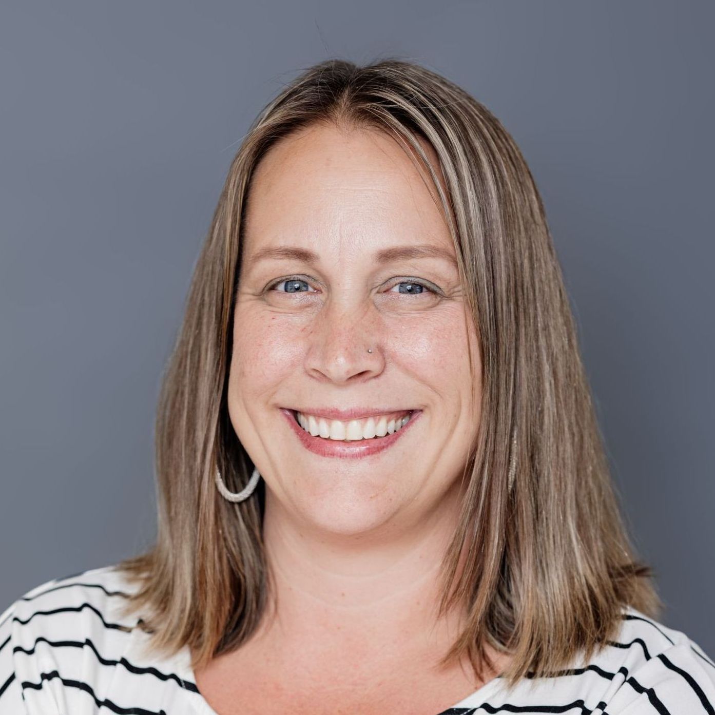 A woman in a striped shirt is smiling for the camera.