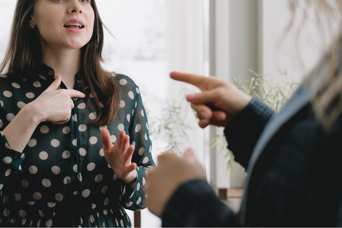 A woman is talking to another woman in an argument and pointing.