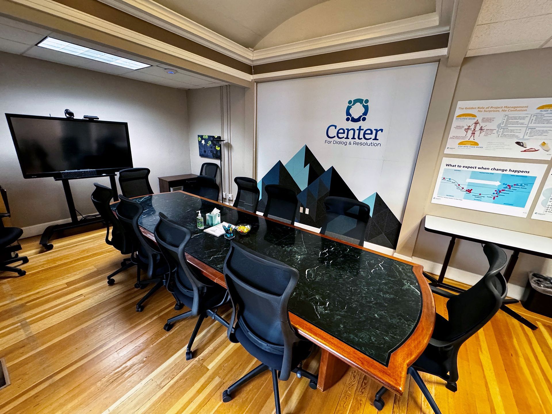 A large conference room with tables and chairs and a large screen on the wall.