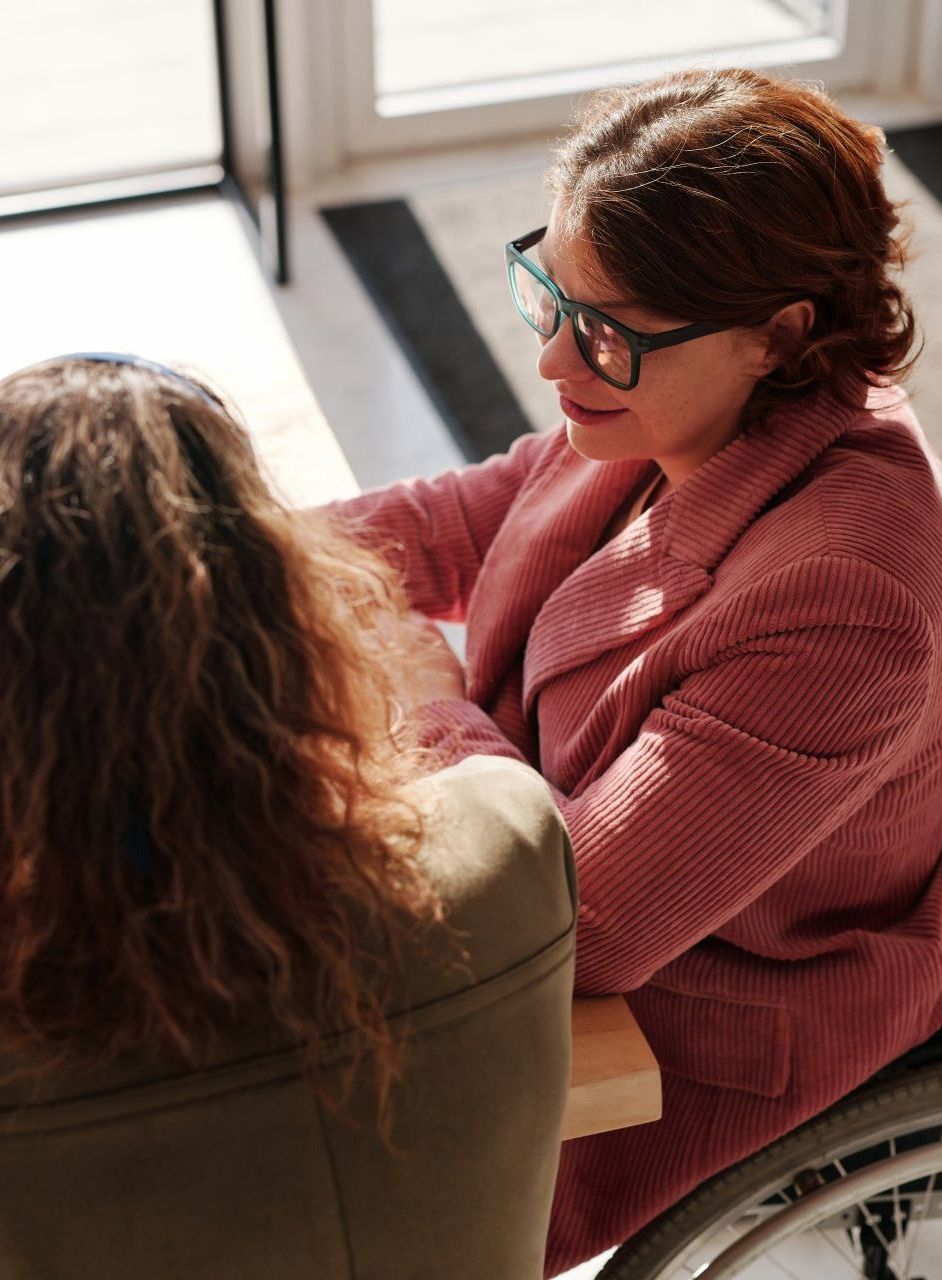 a woman in a wheelchair is talking to another woman