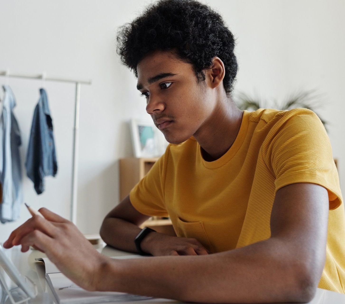 a young man in a yellow shirt is using a laptop computer .