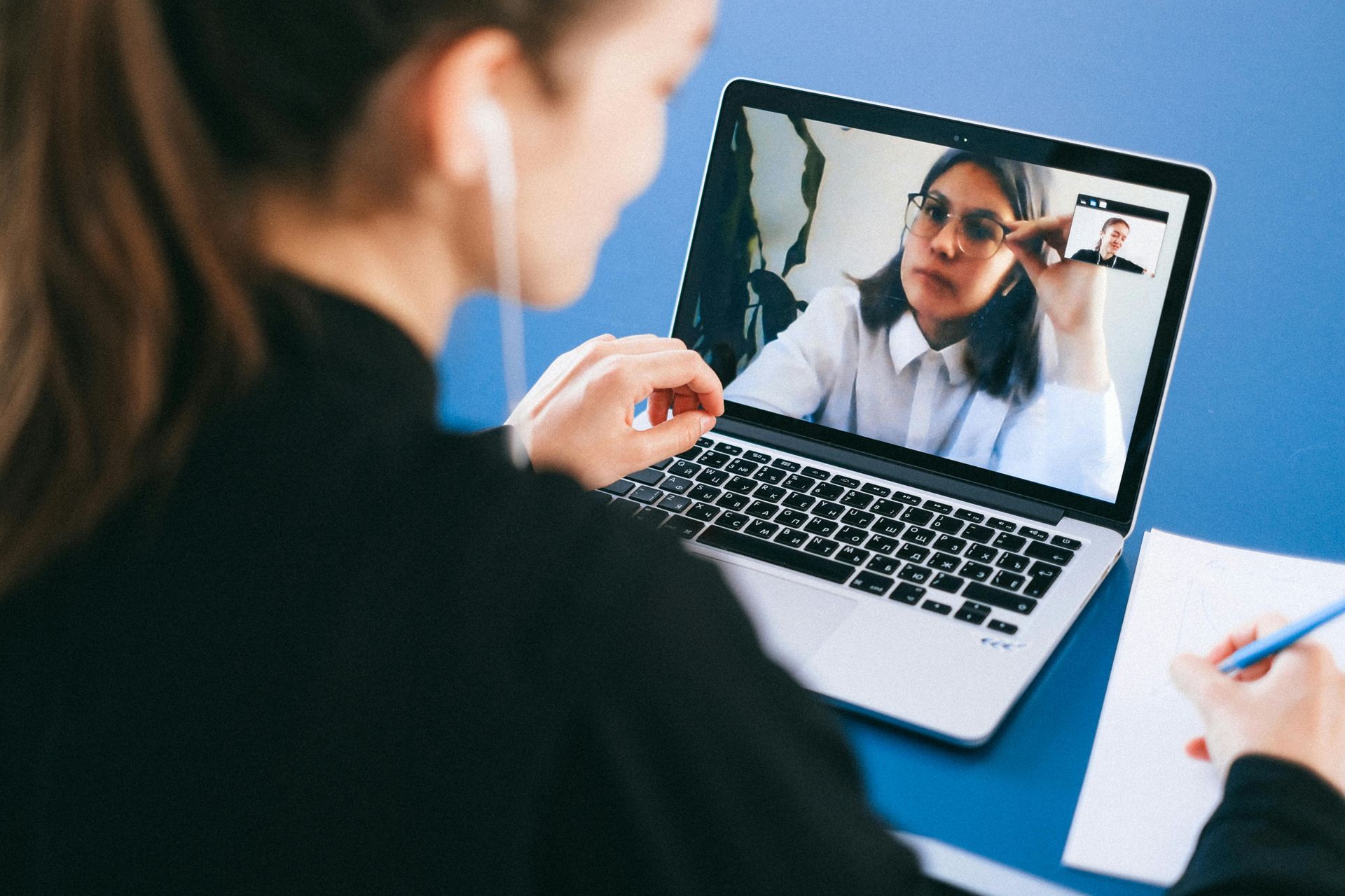A woman is sitting at a desk using a laptop computer.