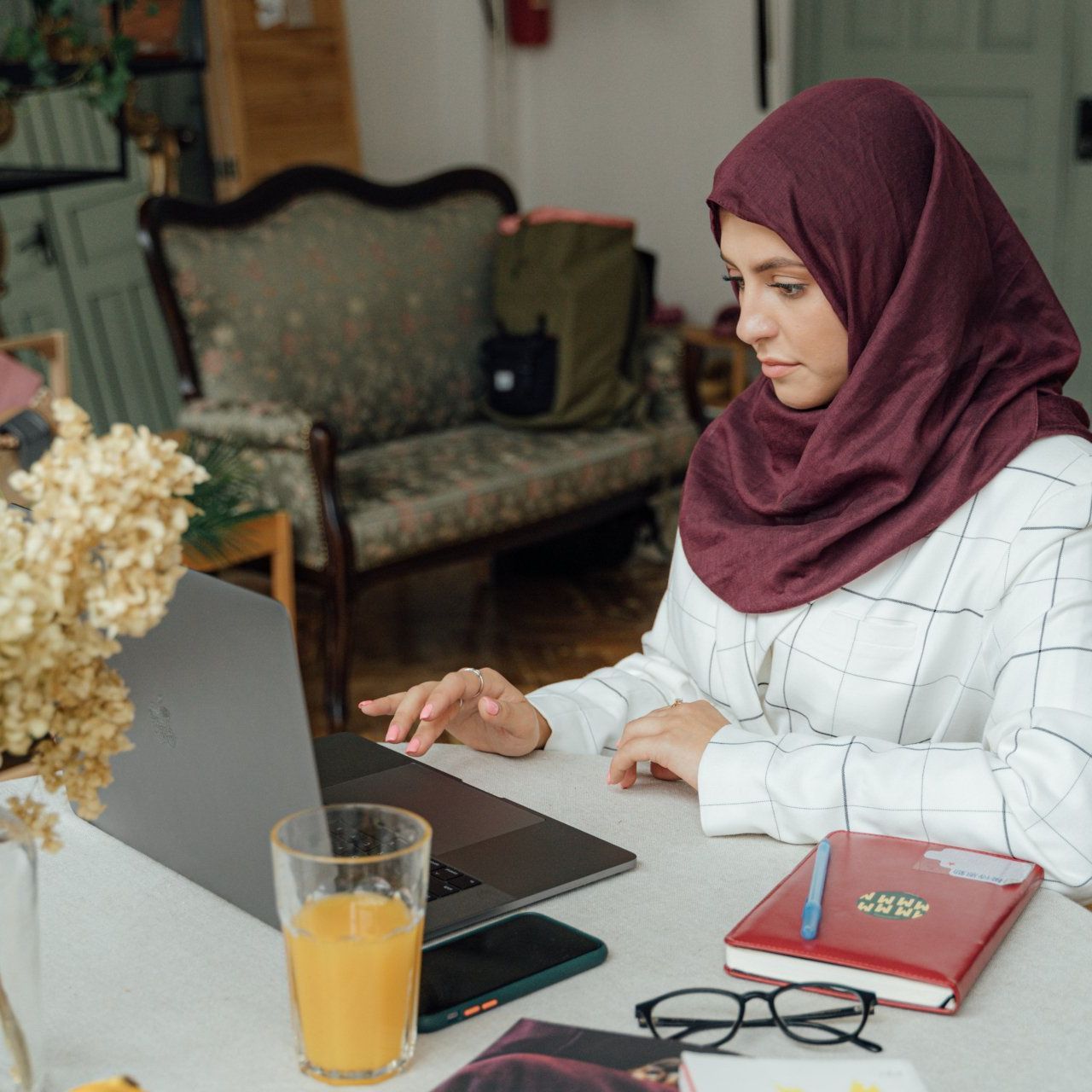 a woman wearing a hijab is working on a laptop