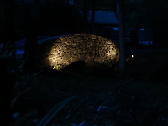 Stone archway illuminated at night.
