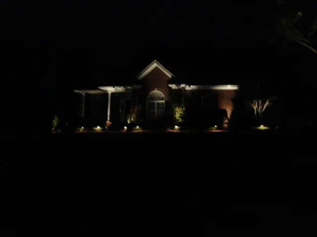 House at night with landscape lighting illuminating the facade.