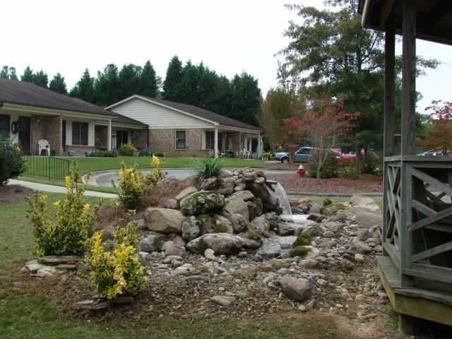 A small waterfall feature in front of a brick building with a gazebo on the right.